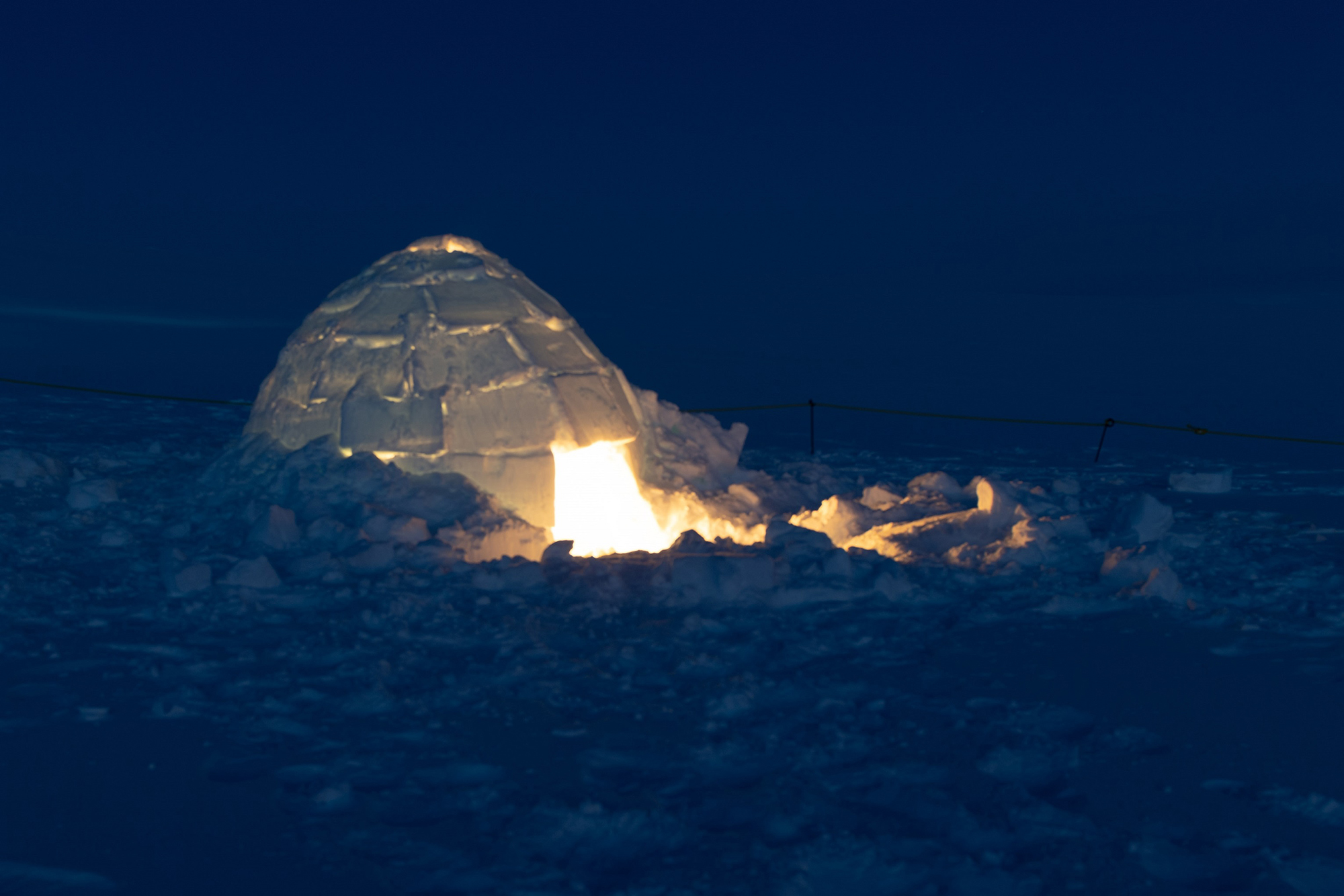 Une photo d’un igloo illuminé pendant la nuit.